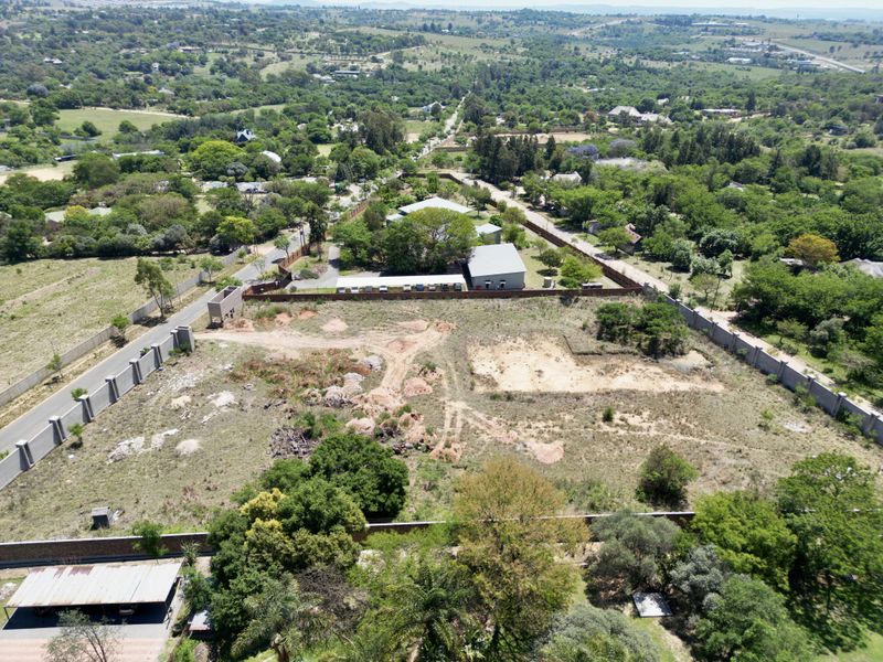 Aerial view of a vacant residential plot featuring perimeter walling and an existing carport structure in a well-established neighborhood.