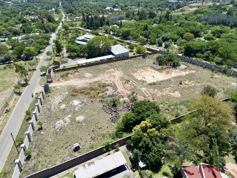 Aerial view of a vacant residential plot featuring perimeter walling and established boundary fencing in a suburban setting.