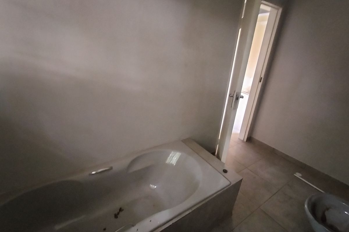 An empty bathroom featuring a built-in bathtub and tiled flooring, currently requiring cosmetic updates and cleaning to restore its functionality.
