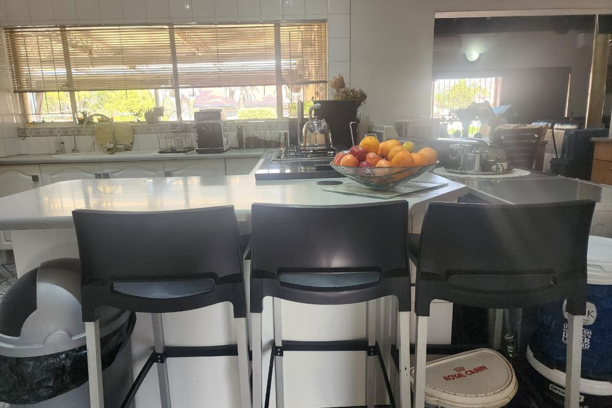A functional kitchen featuring a central island with a gas hob, tiled backsplash, and ample counter space, overlooking an adjacent living area.