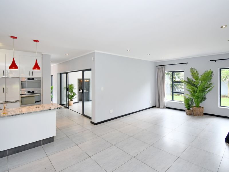 Spacious open-plan living area featuring a modern kitchen with built-in appliances, stone countertops, and large sliding doors leading to the garden.