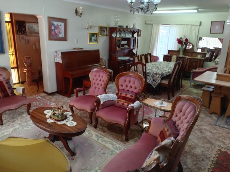 Spacious open-plan living and dining area featuring traditional architectural details, including an archway, wall sconces, and a central chandelier.