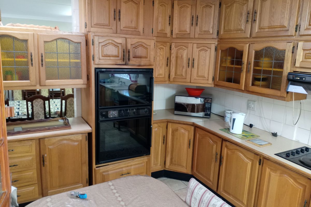 A traditional kitchen featuring extensive oak cabinetry, built-in double oven, laminate countertops, and a tiled backsplash, offering a classic, functional layout.
