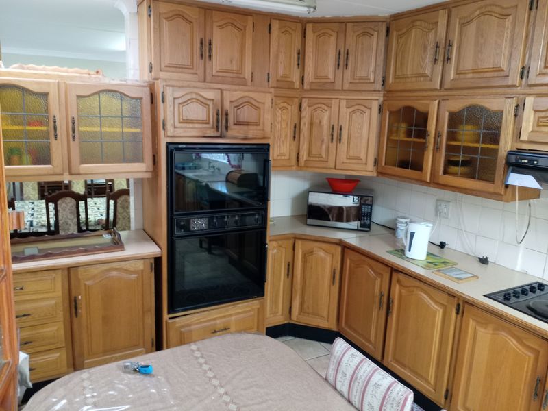 A traditional kitchen featuring extensive oak cabinetry, built-in double oven, laminate countertops, and a tiled backsplash, offering a classic, functional layout.