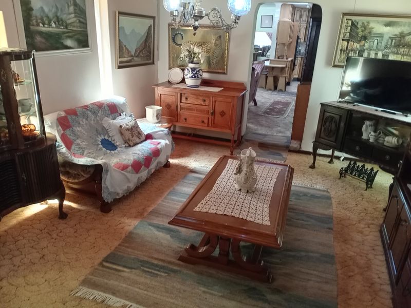 A traditional living room featuring carpeted flooring and an arched entryway leading to the adjacent dining area.
