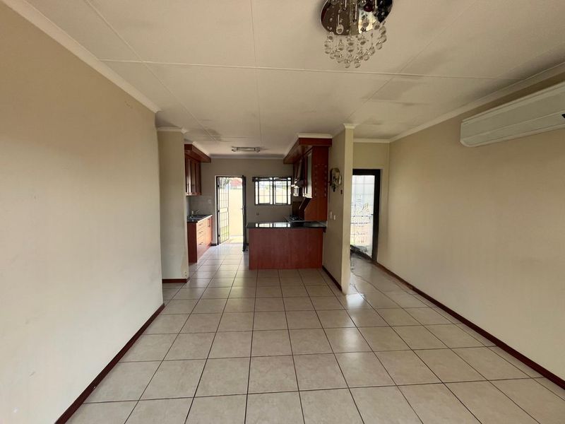 Open-plan living and kitchen area featuring tiled flooring, built-in wooden cabinetry, and a split-system air conditioner.