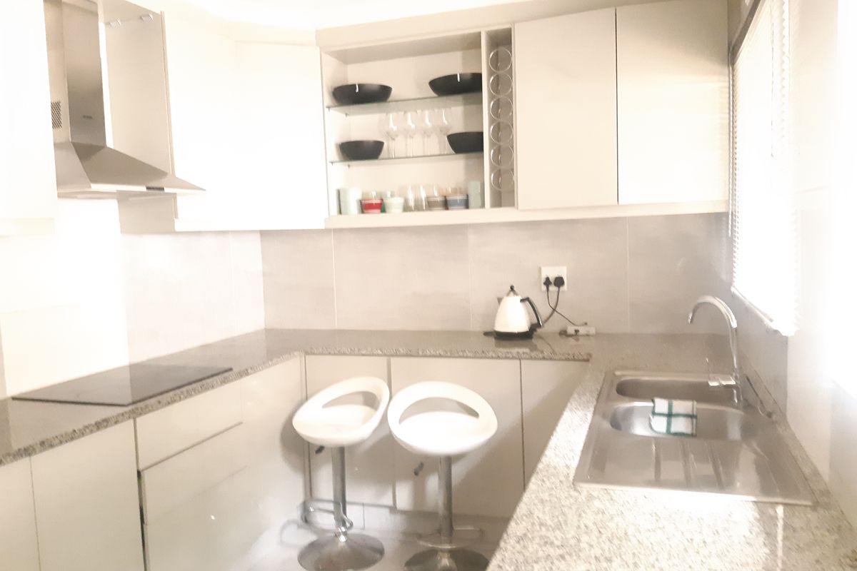 Modern kitchen featuring granite countertops, built-in cabinetry, stainless steel sink, and integrated extractor fan with electric hob.