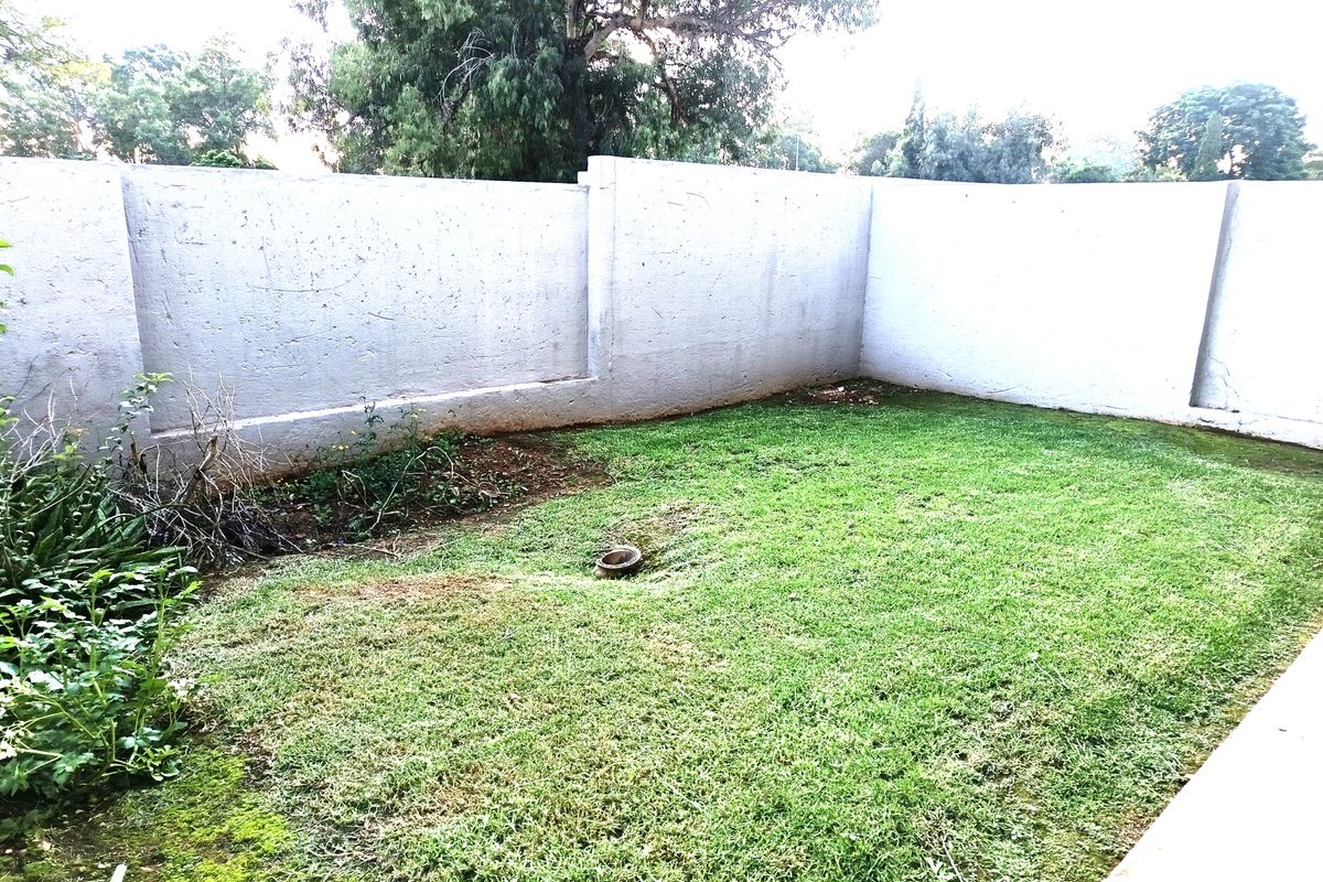 A private rear garden area featuring a lawn and high perimeter boundary walls, offering potential for landscaping and outdoor improvement.