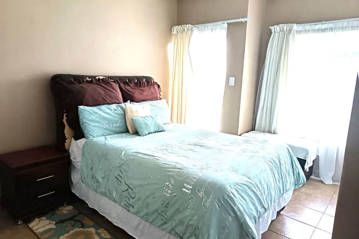 A bedroom featuring tiled flooring and dual windows with curtain tracks, providing natural light to the space.