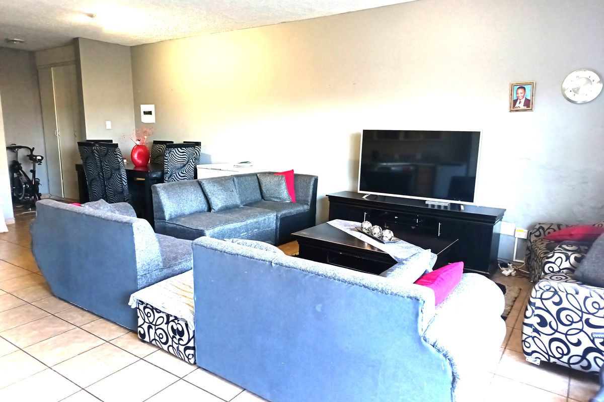 A spacious living area featuring tiled flooring and neutral wall finishes, providing a functional layout for relaxation and dining.