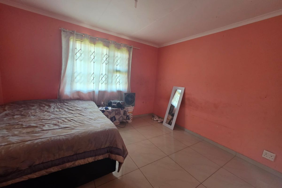 A bedroom featuring tiled flooring and a window with a security gate, currently requiring cosmetic updates to the wall finishes.