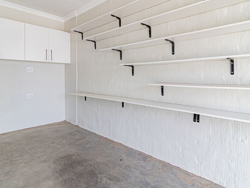A clean, empty garage space featuring extensive wall-mounted shelving and built-in overhead cabinetry, providing ample storage and utility potential.