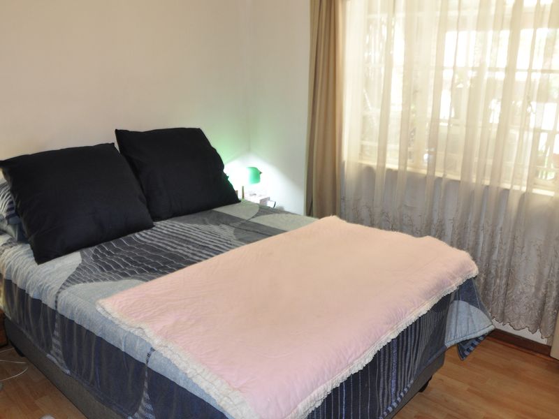 A standard bedroom featuring laminate flooring and window treatments, providing a functional and comfortable living space.