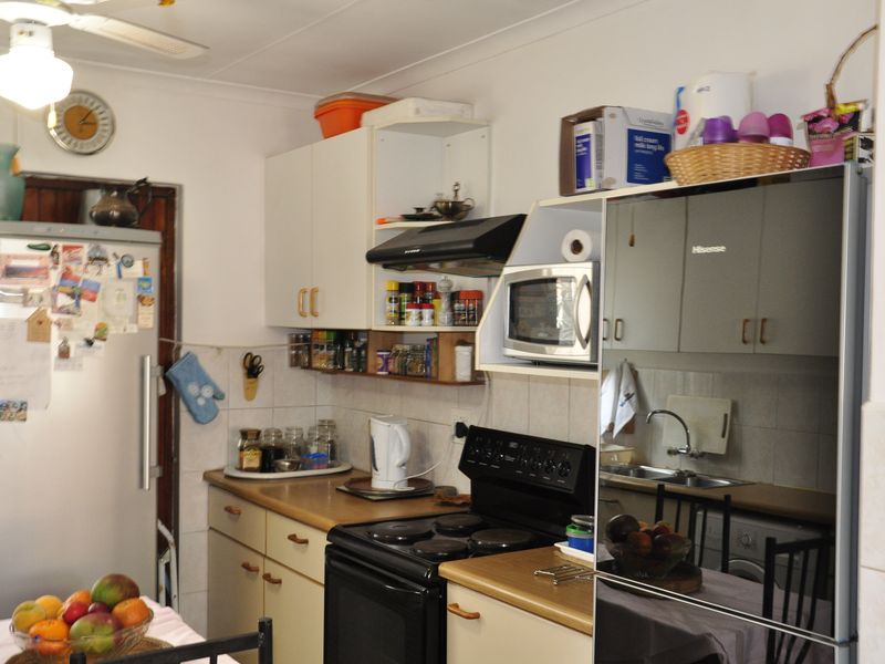 A functional kitchen featuring laminate countertops, built-in cabinetry, a tiled backsplash, and integrated appliances including an extractor fan and microwave.