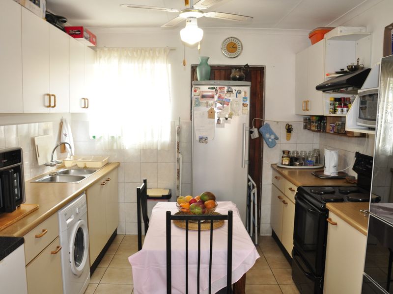 A functional kitchen featuring white cabinetry, laminate countertops, tiled backsplash, and integrated appliances, offering a practical layout for daily meal preparation.