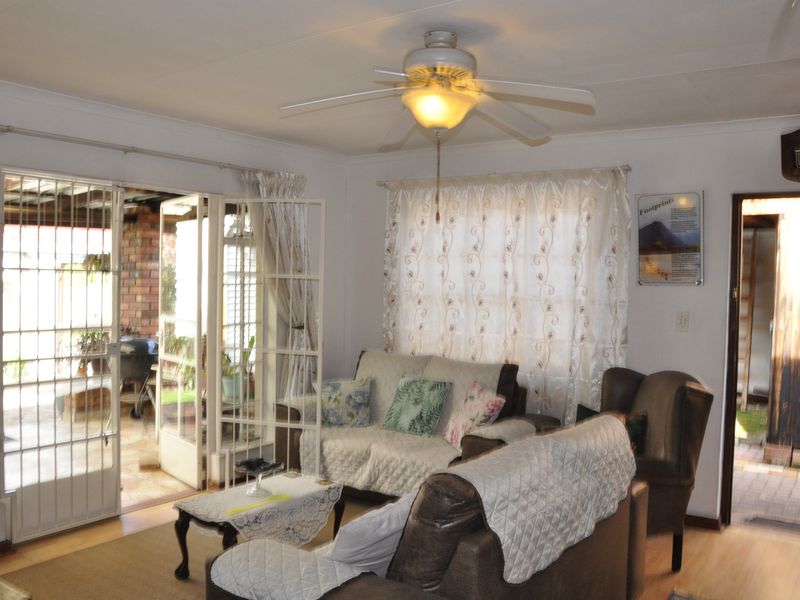 A comfortable living room featuring laminate flooring, a ceiling fan, and direct access to an outdoor patio through glass french doors.