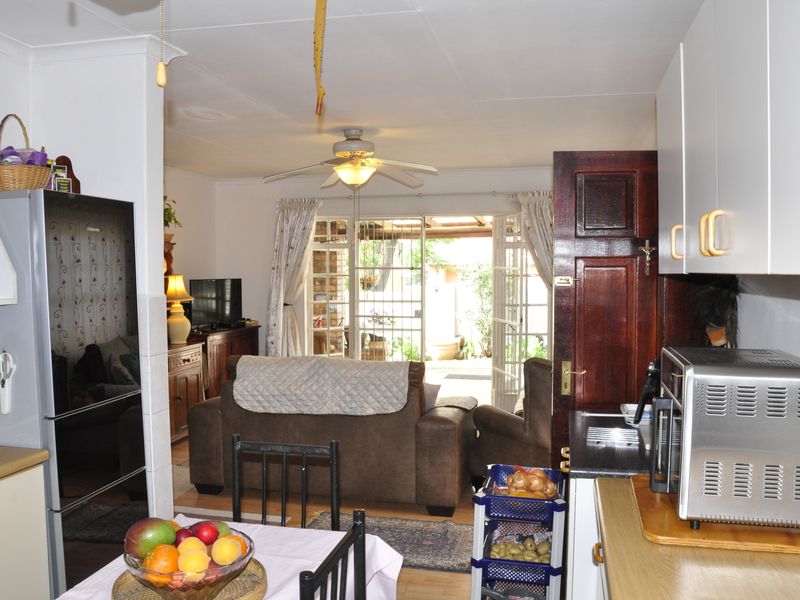 Open plan kitchen and living area featuring laminate flooring, ceiling fan, and direct access to the rear patio through glass french doors.