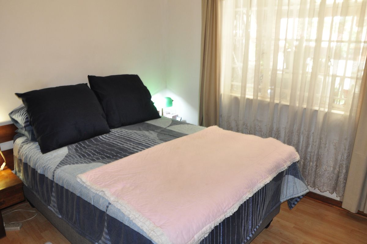 A standard bedroom featuring laminate flooring and window treatments, providing a functional and comfortable living space.