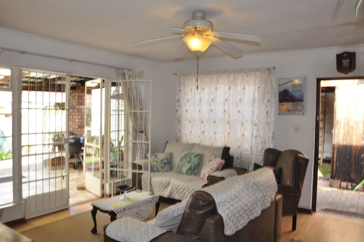 A comfortable living room featuring laminate flooring, a ceiling fan, and direct access to an outdoor patio through glass french doors.