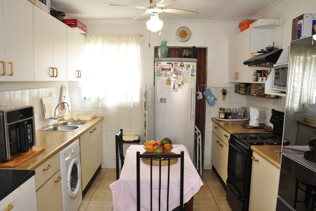 A functional kitchen featuring white cabinetry, laminate countertops, tiled backsplash, and integrated appliances, offering a practical layout for daily meal preparation.