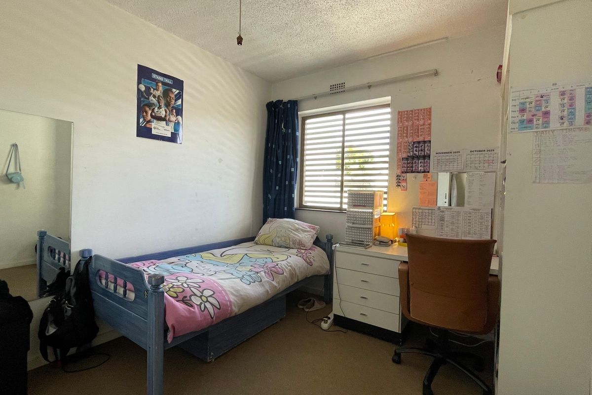 A compact bedroom featuring carpeted flooring, a window with fitted blinds, and standard interior finishes.