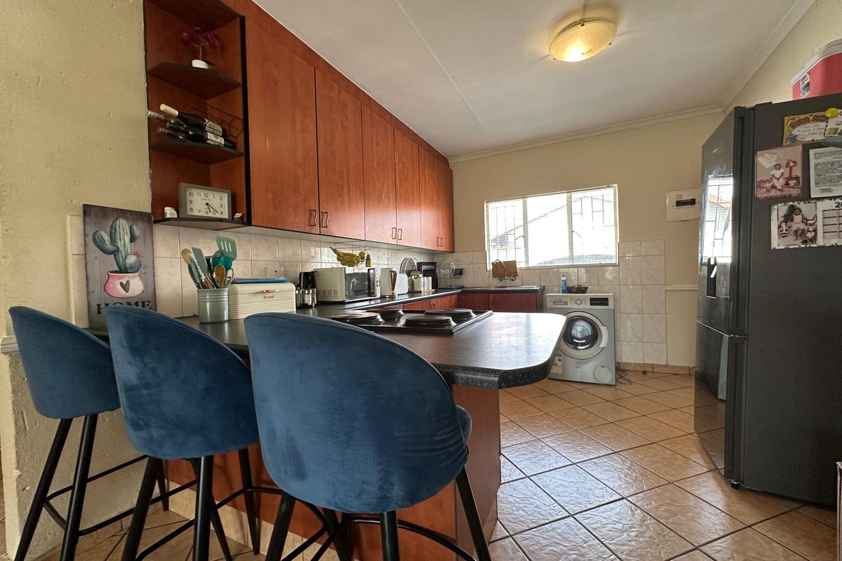A functional kitchen featuring wood-tone cabinetry, laminate countertops, ceramic tile backsplash, and tiled flooring, offering a practical layout for daily use.