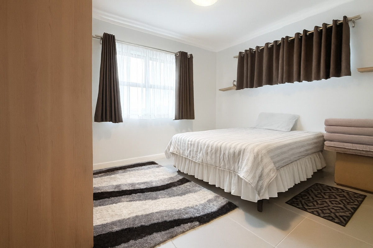 A bright bedroom featuring tiled flooring, neutral walls, and built-in curtain rods, offering a clean and functional living space.