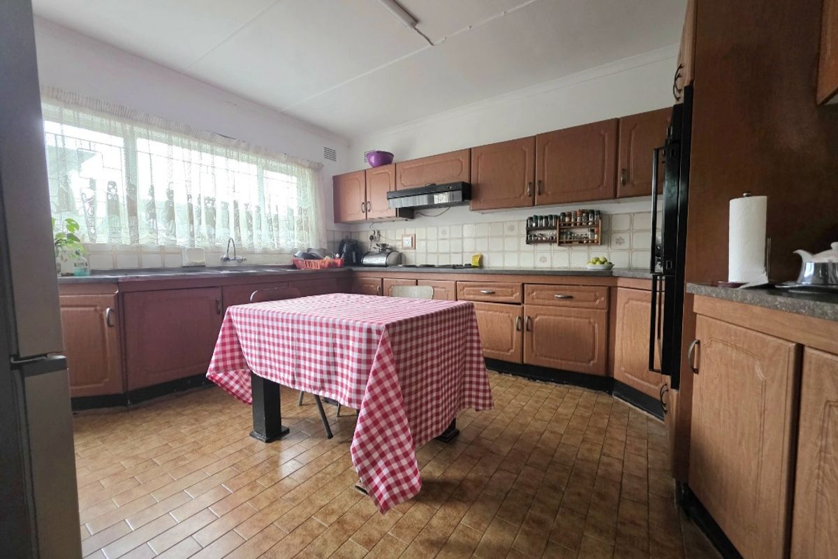 A spacious kitchen featuring traditional wood-finish cabinetry, tiled backsplash, and ample counter space, offering a functional layout ready for modern updates.