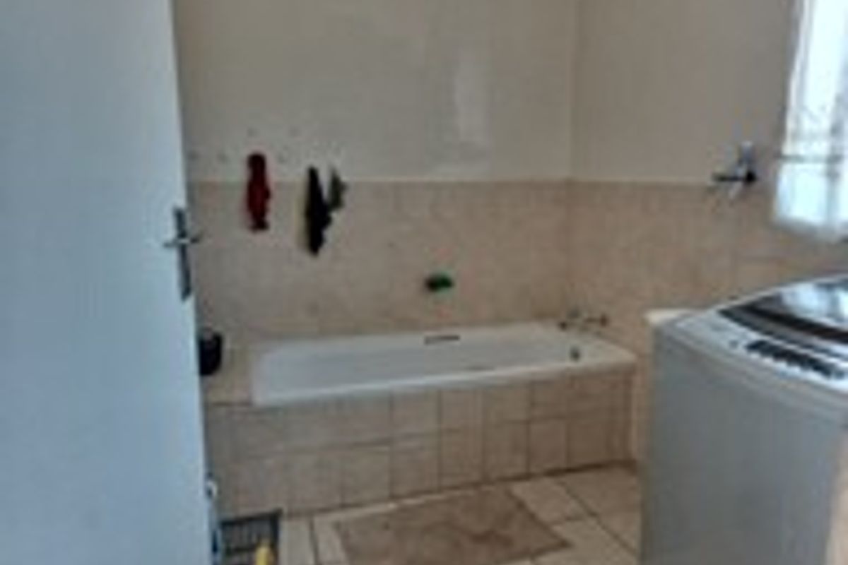 A functional bathroom featuring a built-in bathtub with tiled surround and wall-mounted fixtures, providing a practical space for daily use.
