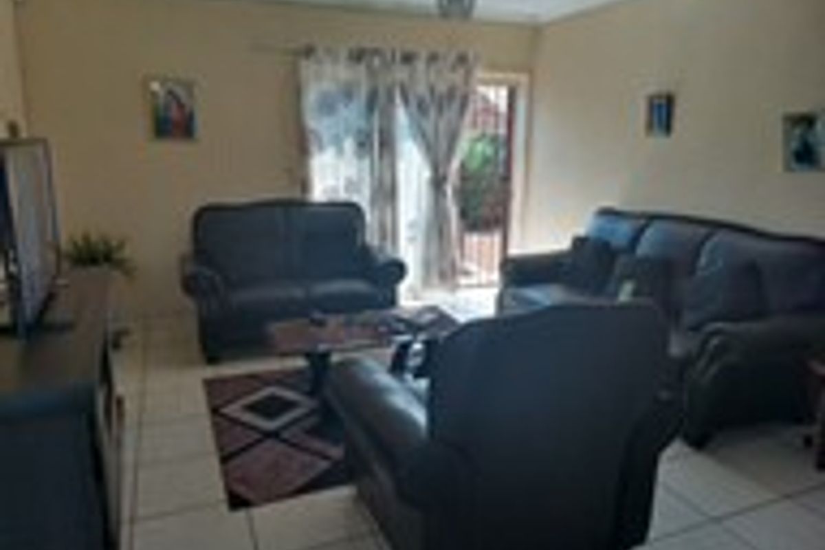 A living room featuring tiled flooring and sliding glass doors providing access to the exterior.