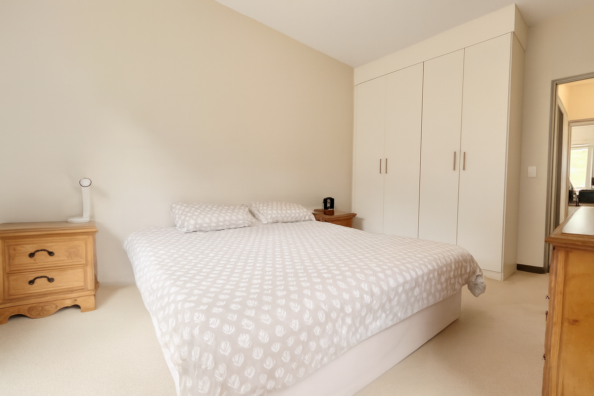 A well-maintained bedroom featuring neutral carpeting and ample built-in storage cupboards.