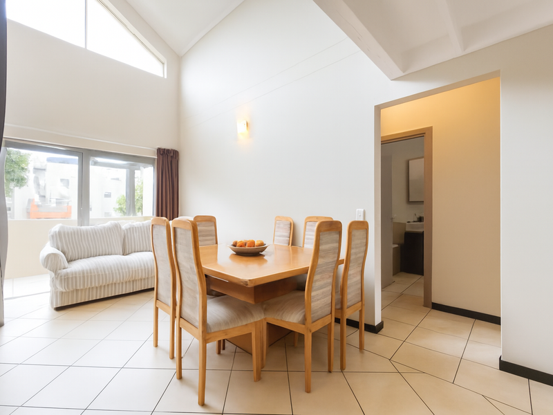 Spacious open-plan dining area featuring high vaulted ceilings, tiled flooring, and abundant natural light from large windows and a sliding door.