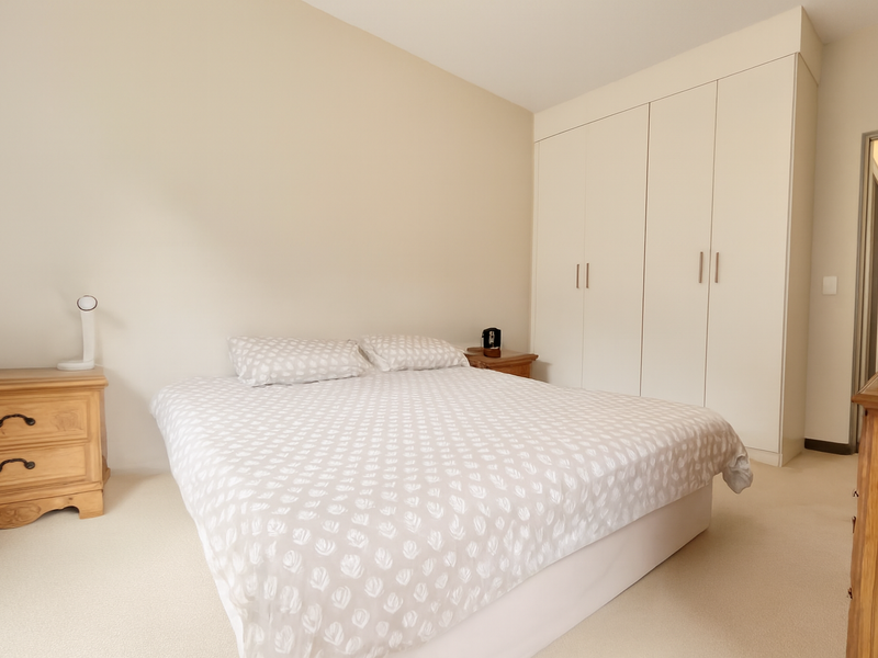 A well-maintained bedroom featuring neutral carpeting and ample built-in storage cupboards.
