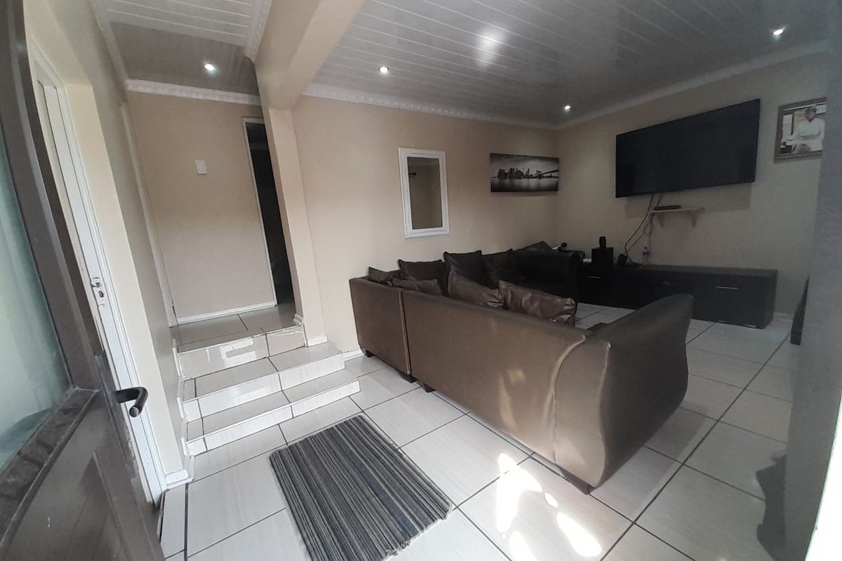 A living room featuring tiled flooring, recessed ceiling lighting, and a coved ceiling, with an internal staircase leading to an adjacent area.