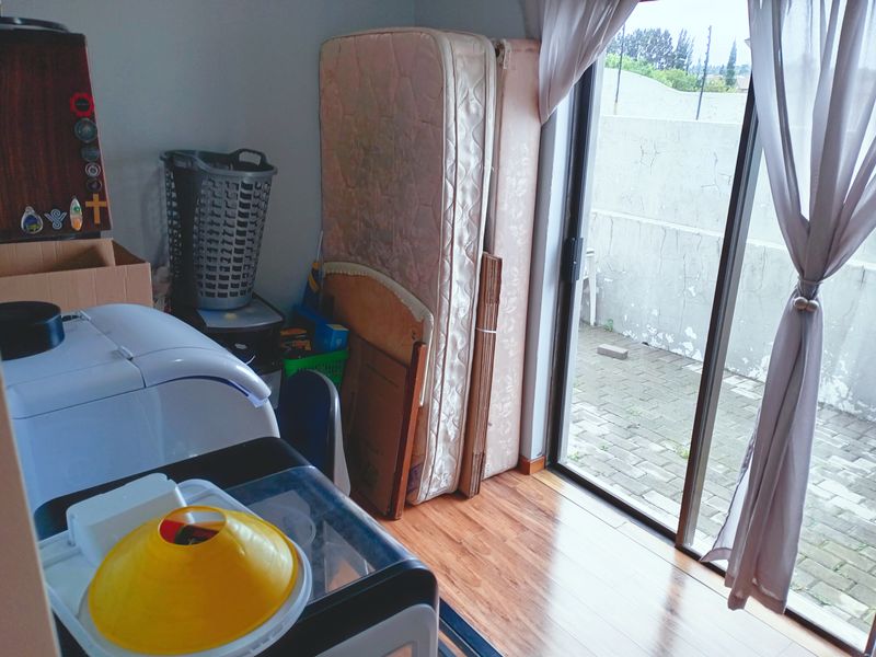 A utility or laundry space featuring laminate flooring and a sliding glass door providing direct access to a paved outdoor patio area.