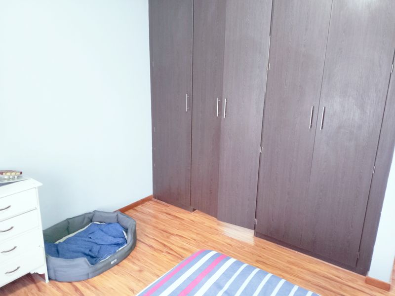 A bedroom featuring dark wood-finish built-in cupboards and laminate flooring, providing ample storage space.