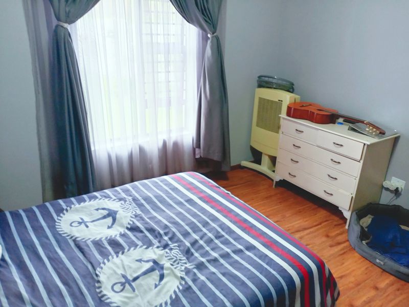 A bedroom featuring laminate flooring and a window with installed curtain tracks.