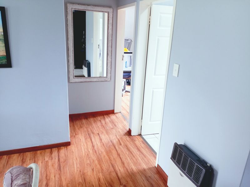 A functional hallway featuring laminate flooring and access to adjacent rooms through internal doors.