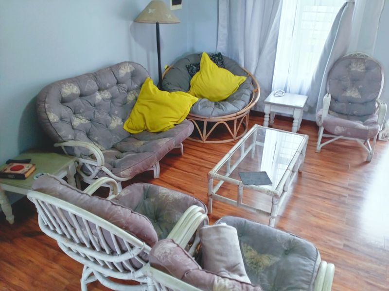 A cozy living room area featuring warm-toned laminate flooring and natural light from the window.