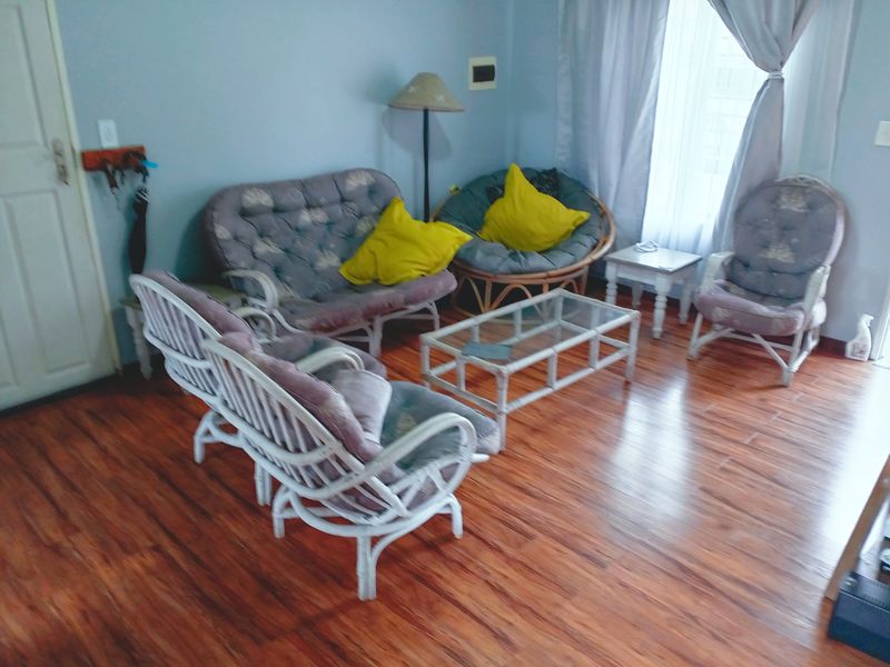 A living room area featuring laminate wood-look flooring and neutral wall finishes, providing a functional space for relaxation.