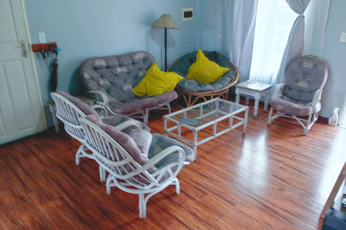 A living room area featuring laminate wood-look flooring and neutral wall finishes, providing a functional space for relaxation.