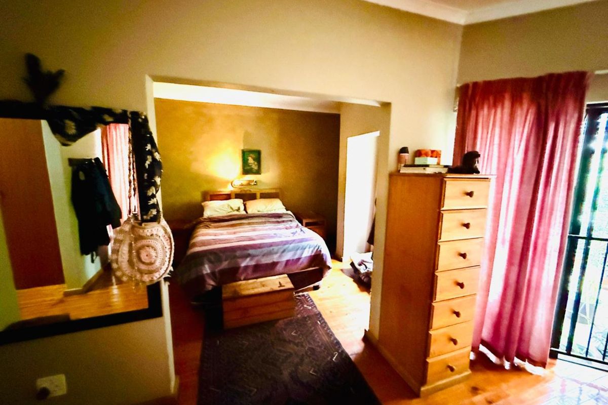 A bedroom featuring wooden flooring, a recessed sleeping area, and access to an outdoor space through a glass door.