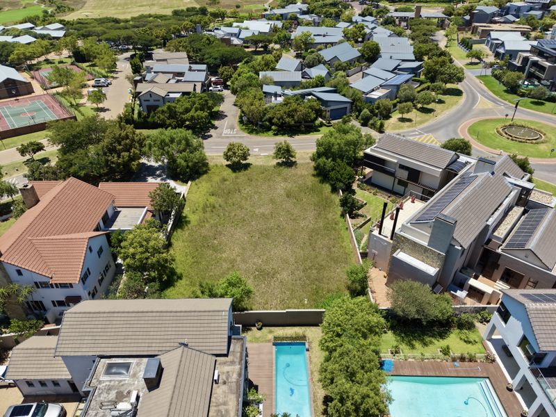 Aerial view of a vacant residential plot situated within a developed estate, surrounded by existing homes and established landscaping.