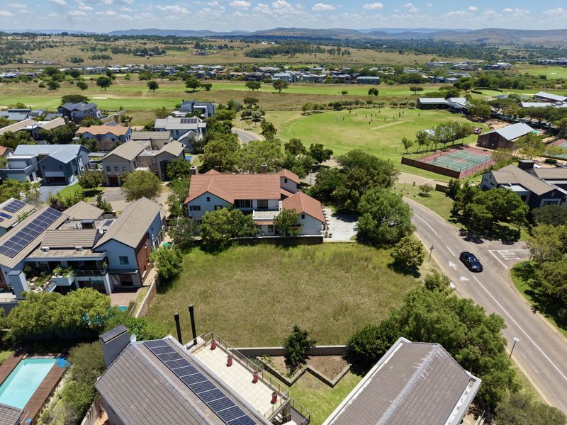 An aerial view of a vacant residential plot situated within a developed estate, offering ample space for new construction.