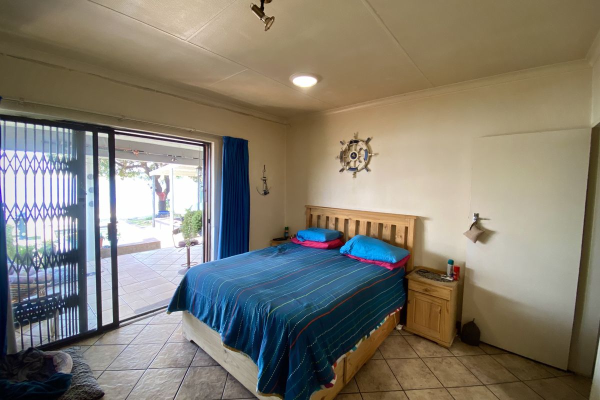 A bedroom featuring tiled flooring and a sliding glass door with a security gate, providing direct access to an outdoor patio area.