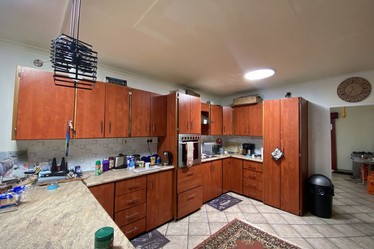 A functional kitchen featuring wood-look laminate cabinetry, tiled flooring, and a built-in oven, offering a dated aesthetic with potential for modern updates.