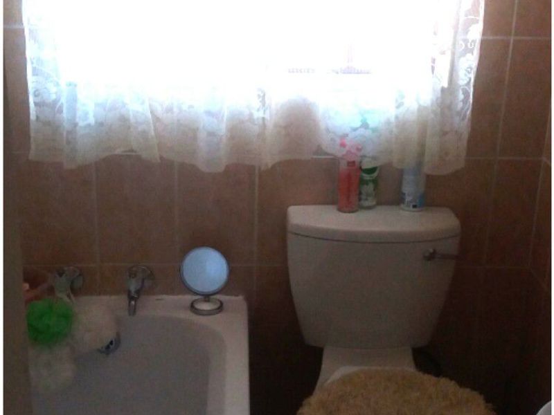 A compact bathroom featuring a standard bathtub and toilet with tiled wall and floor finishes.