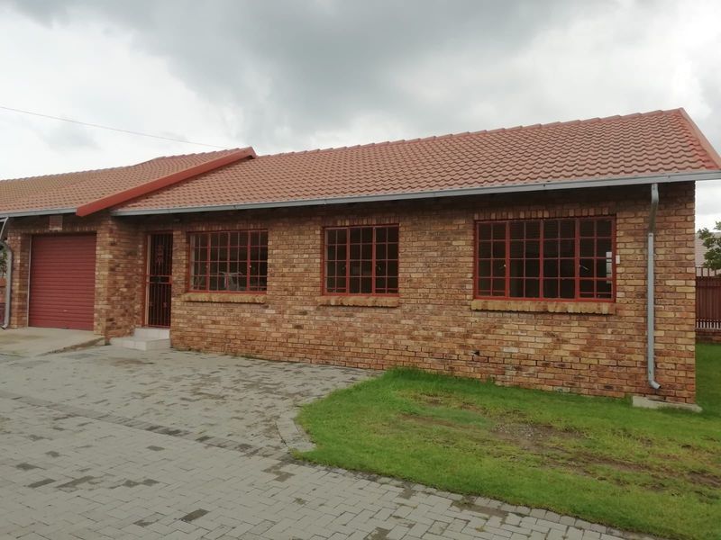 A well-maintained face brick house featuring a tiled roof, paved driveway, and secure garage access.