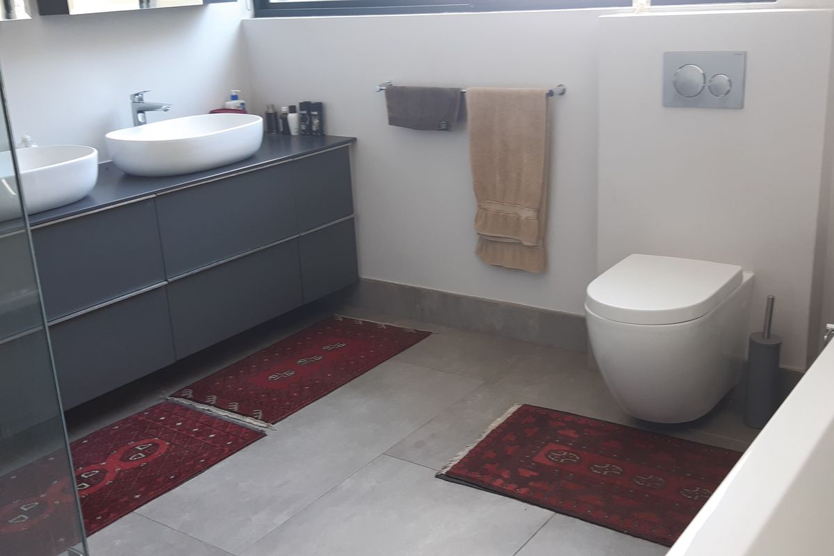 Modern bathroom featuring a double vanity with vessel sinks, a wall-mounted toilet with concealed cistern, a glass shower enclosure, and a freestanding bathtub.