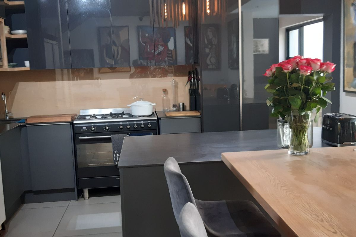 Modern kitchen featuring dark cabinetry, stone countertops, a central island, and a gas stove, offering a sleek and functional cooking space.